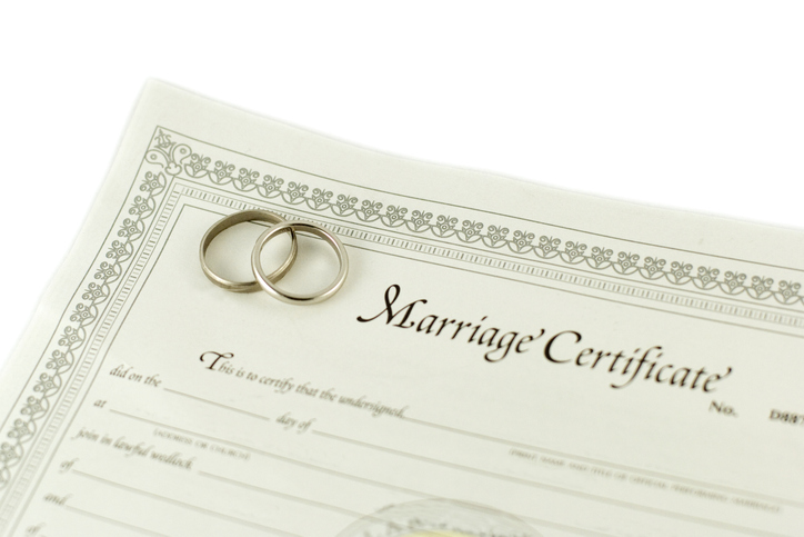 marriage certificate legal document with 2 wedding bands on it